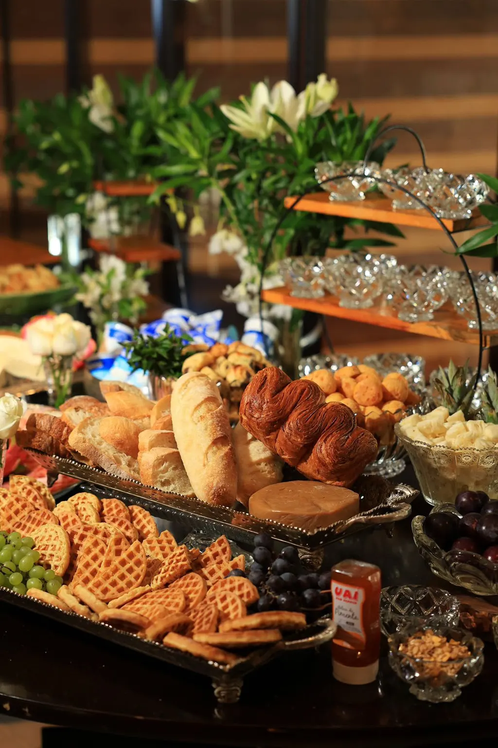 Mesa de café com pães, waffles, flores brancas e cristais
