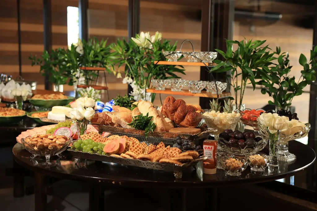 Mesa de café com pães, waffles, frutas, flores e cristais